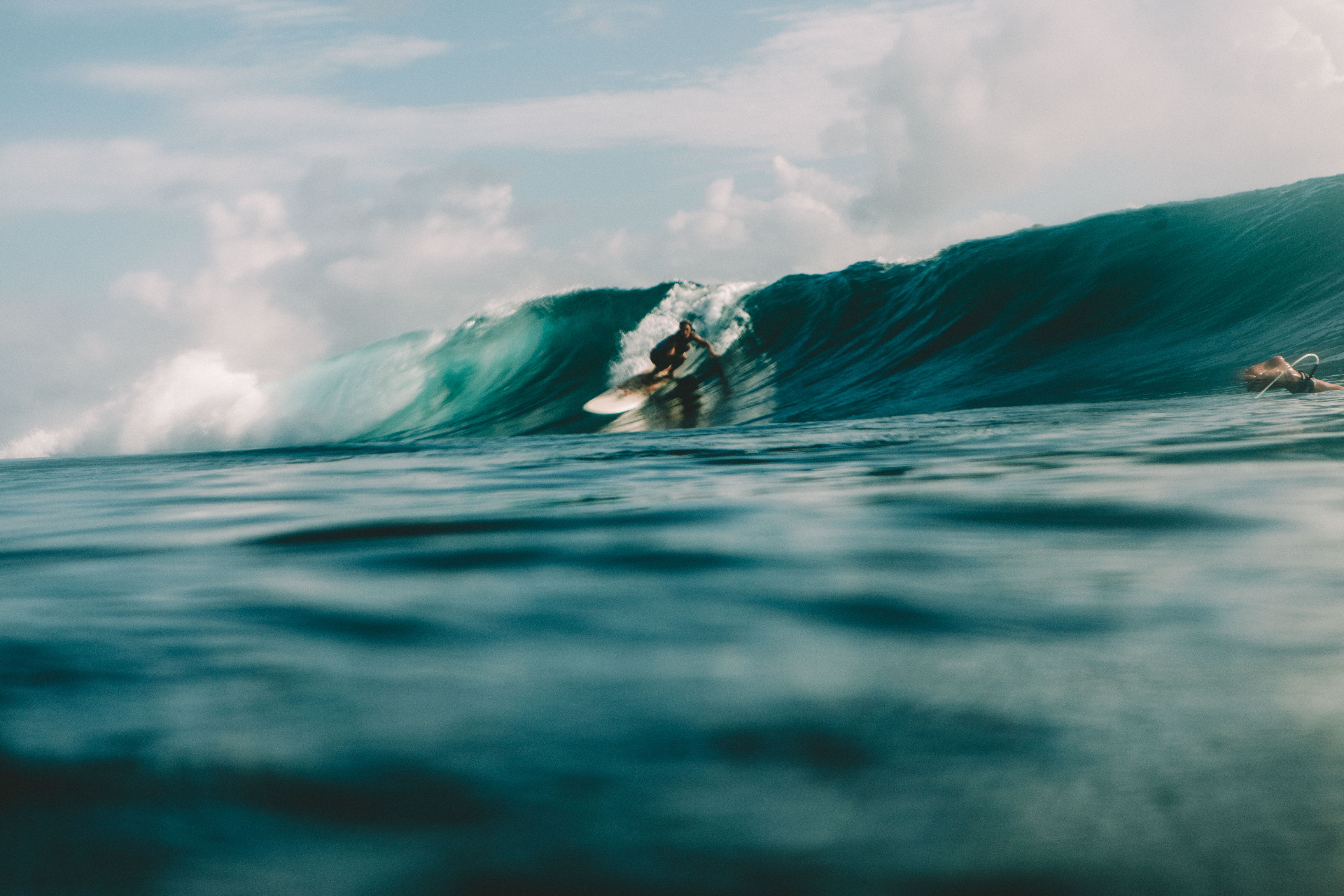 Surfer riding a peeling turquoise wave from water level