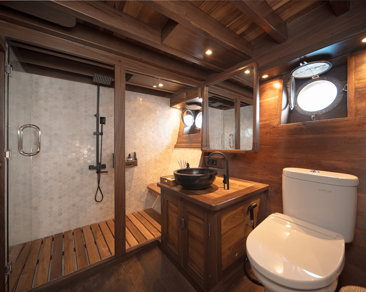 Sanya ensuite bathroom with walk-in rain shower, stone basin and porthole windows
