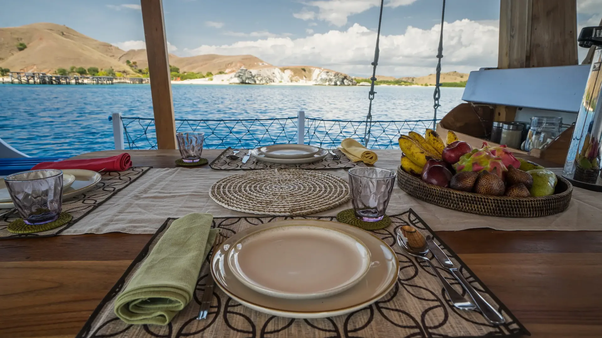 Table set for a meal on Jinggo Janggo with fresh fruit and views of a white sand beach