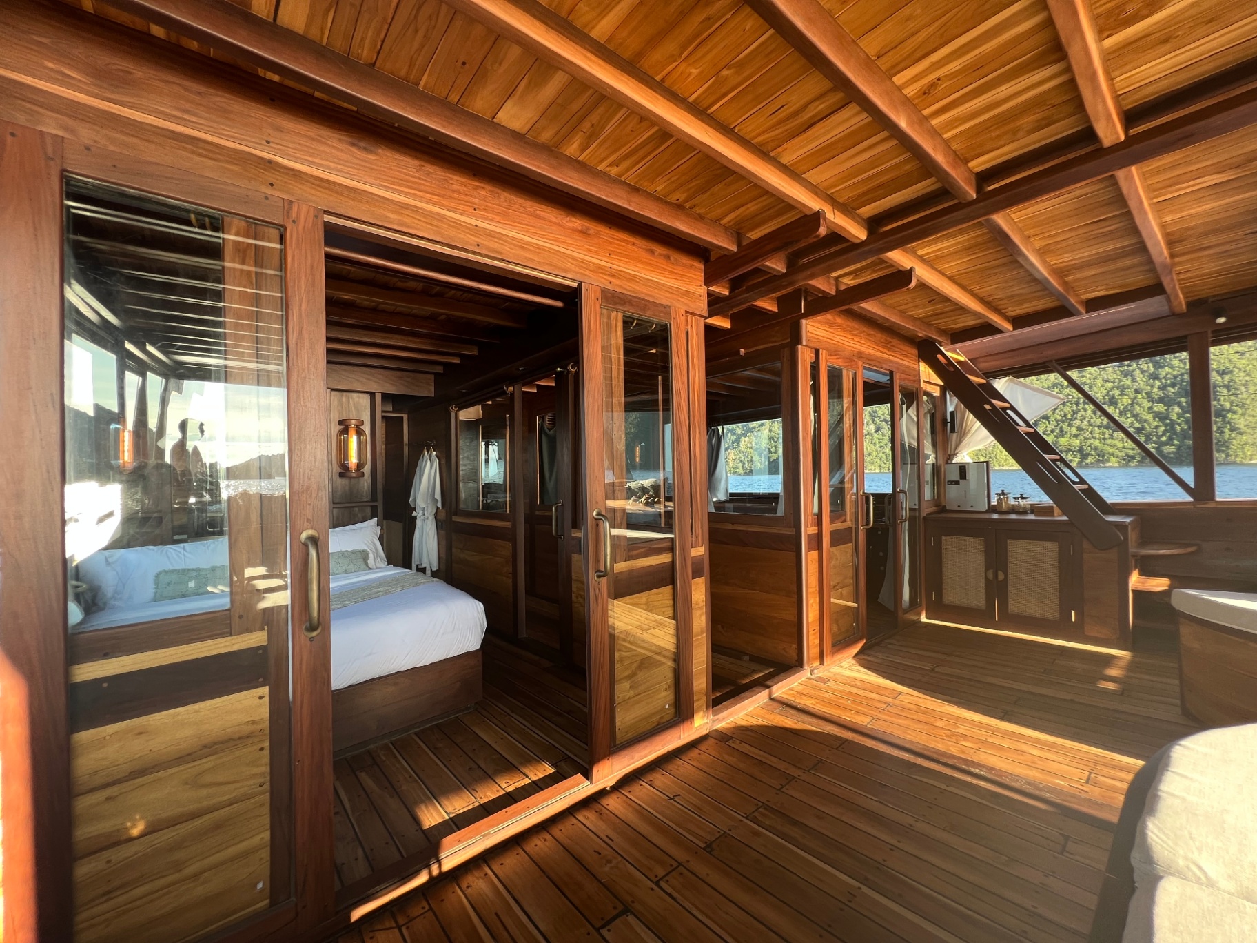 Dewata master cabin deck with warm teak floors and open sliding doors to the sea