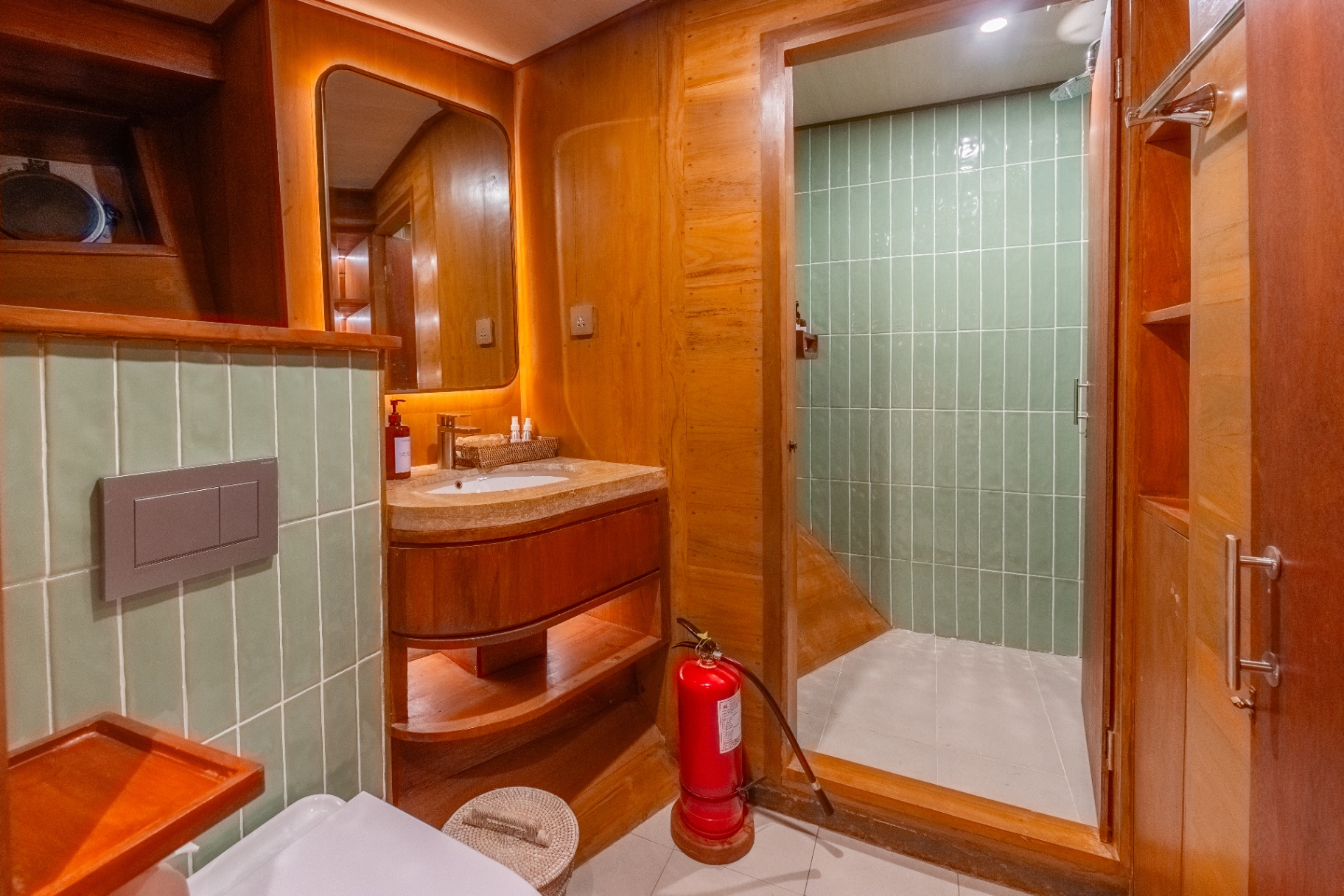 Lower-deck ensuite on Sanctuary with walk-in rain shower, green tiled walls and stone vanity