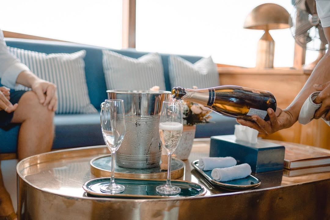Close-up of champagne being poured into flutes on a brass tray in Samara II's saloon
