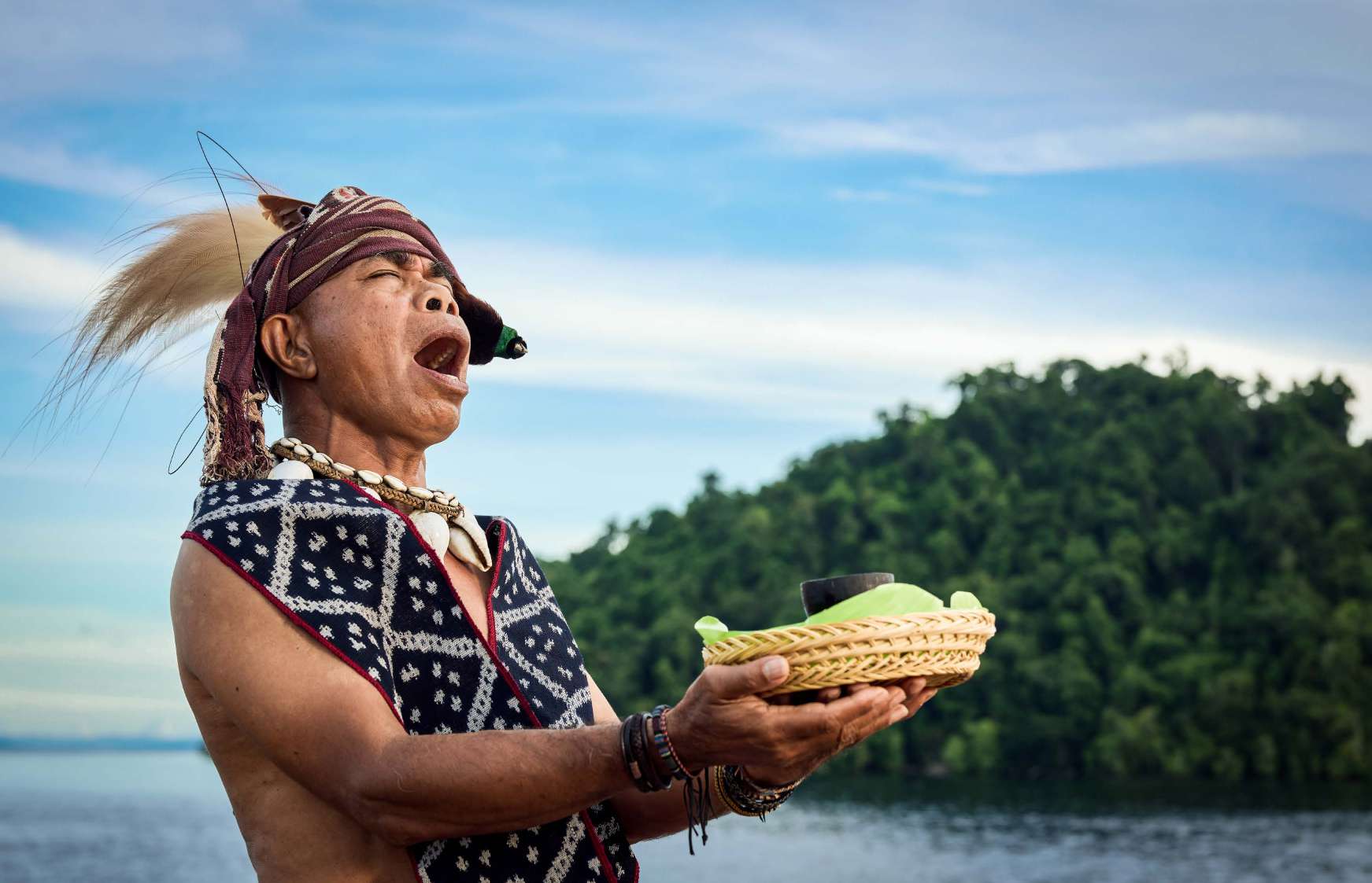 Local man in traditional attire holding a woven basket with spices on a Spice Route village visit