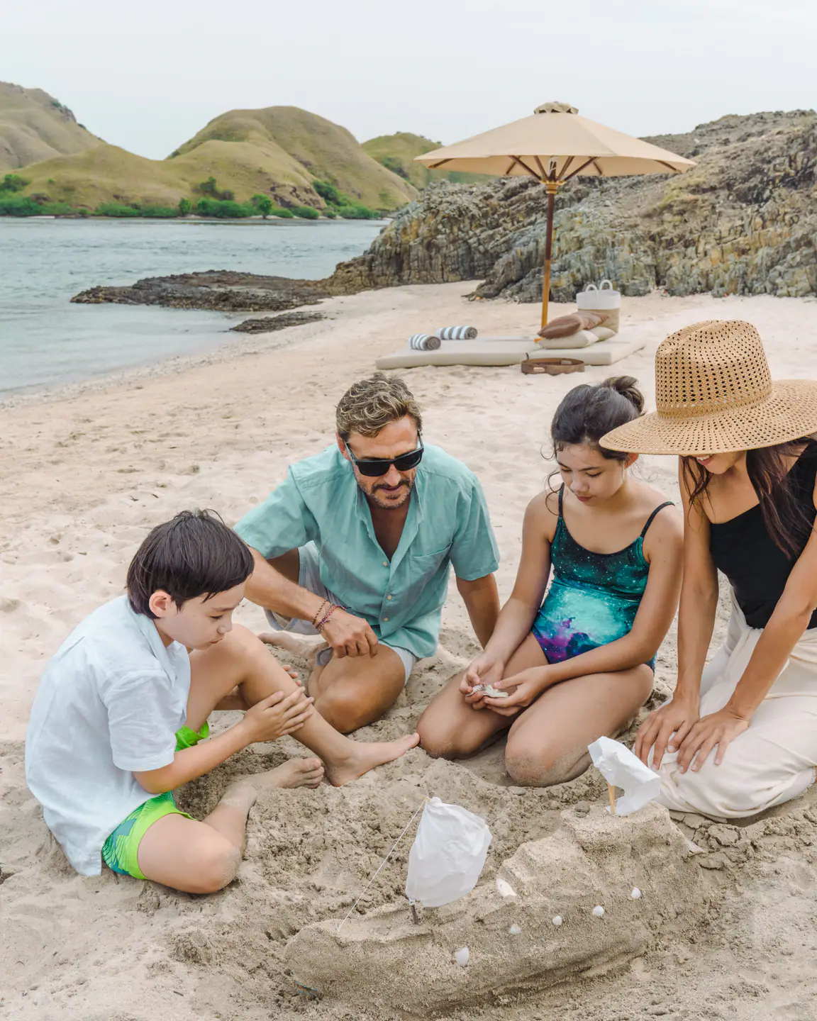 Family building sandcastles on a private beach during a Celestia charter