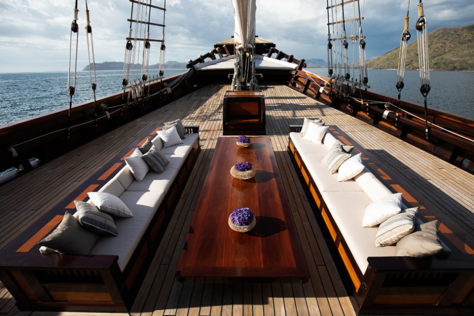 Symmetrical teak foredeck lounge with facing sofas and low table