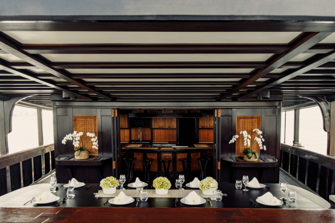 Formal indoor dining table set for service with orchids and bar behind
