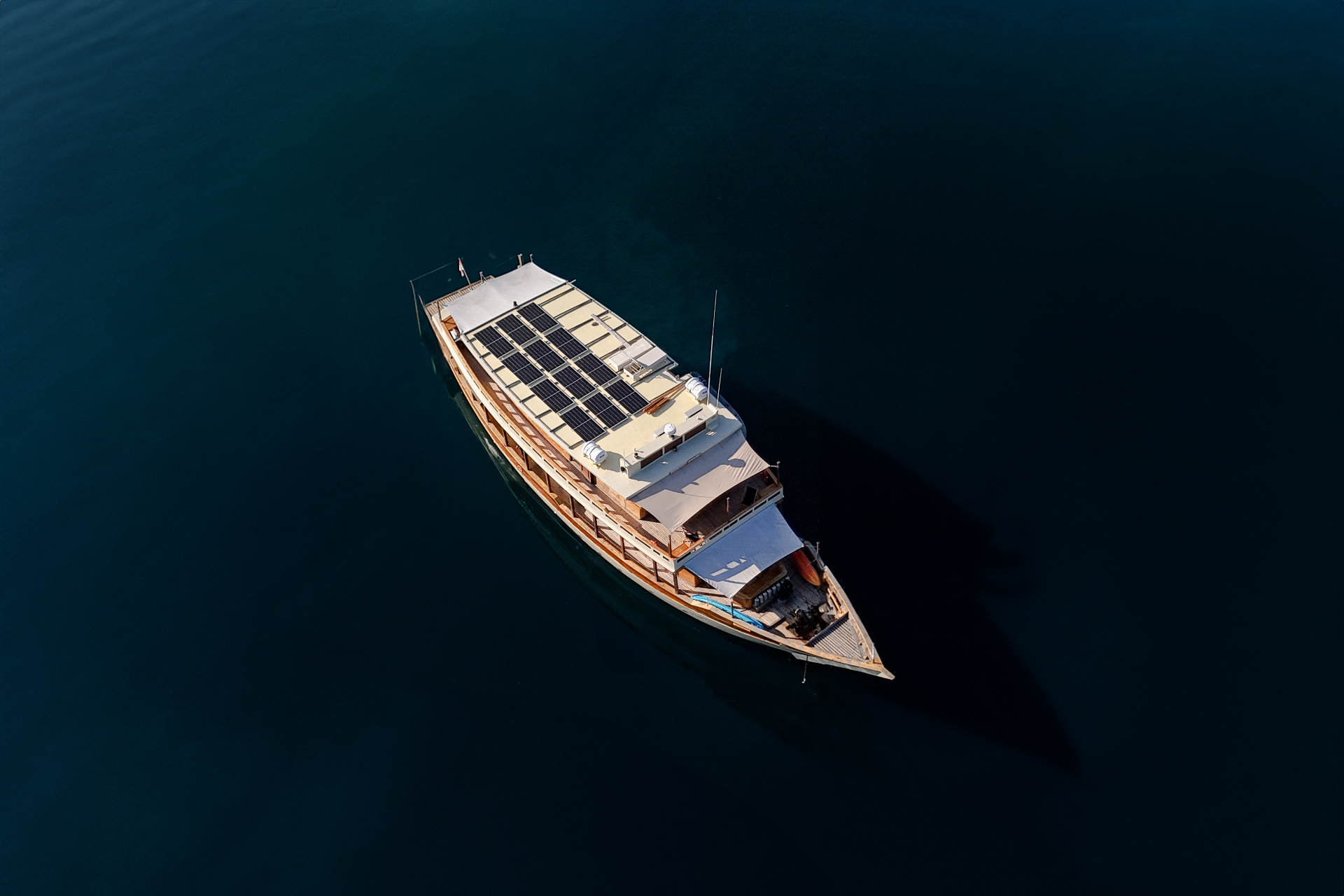 Overhead view of Mischief's solar-panelled sundeck on glassy midnight-blue water