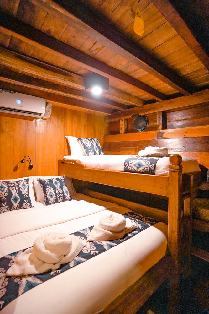 Bunk cabin on Adishree with warm teak panelling, porthole window and turned-down beds