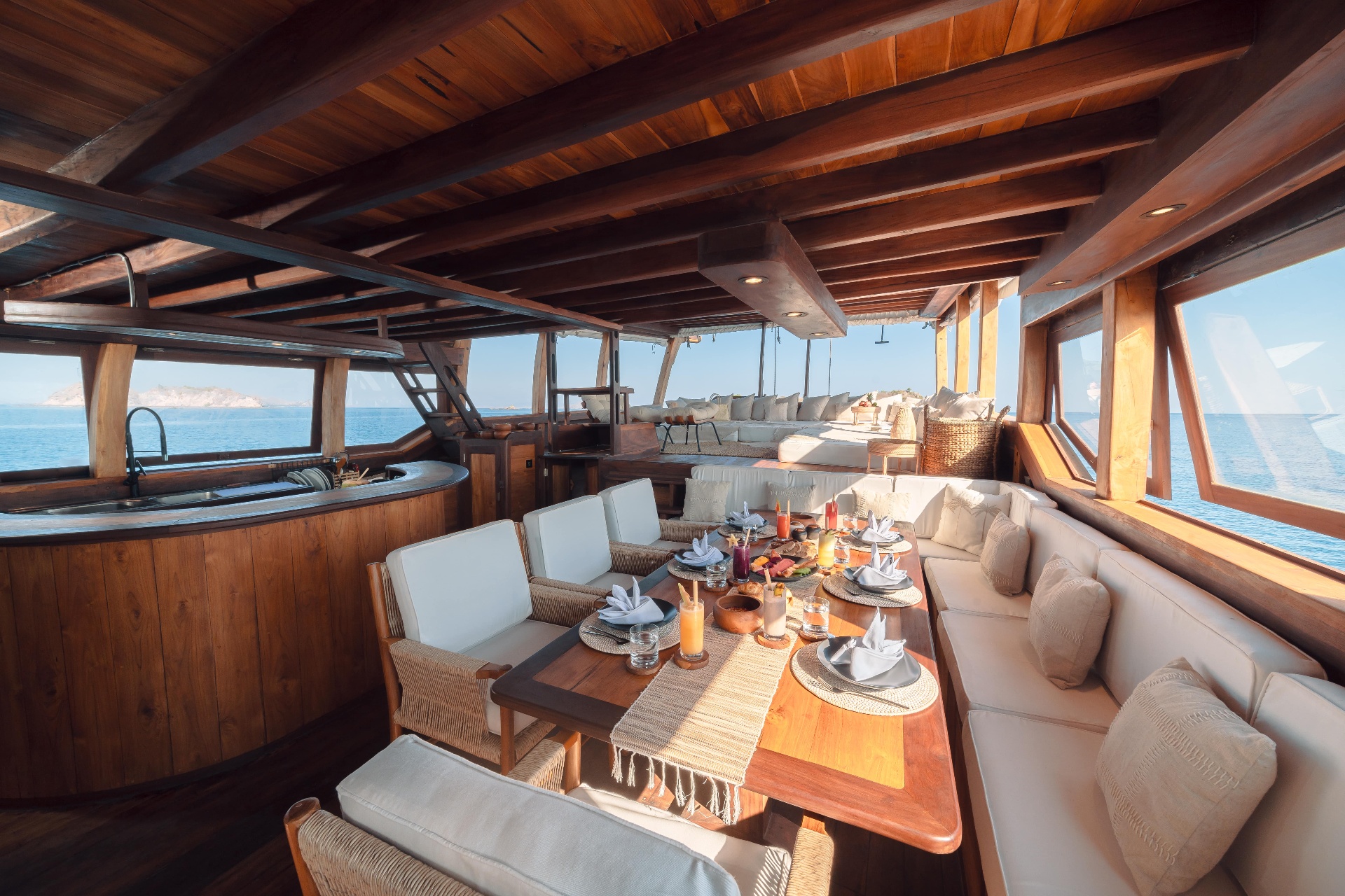 Main-deck dining table on Nataraja set for breakfast with fresh juices, plates and cushioned bench seating