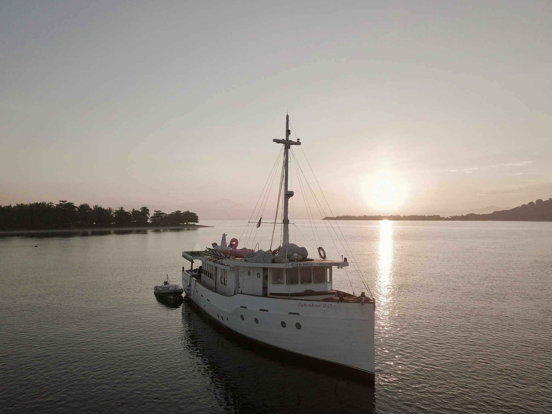 Splendour anchored at golden sunset with still water reflections and the upper deck visible in silhouette