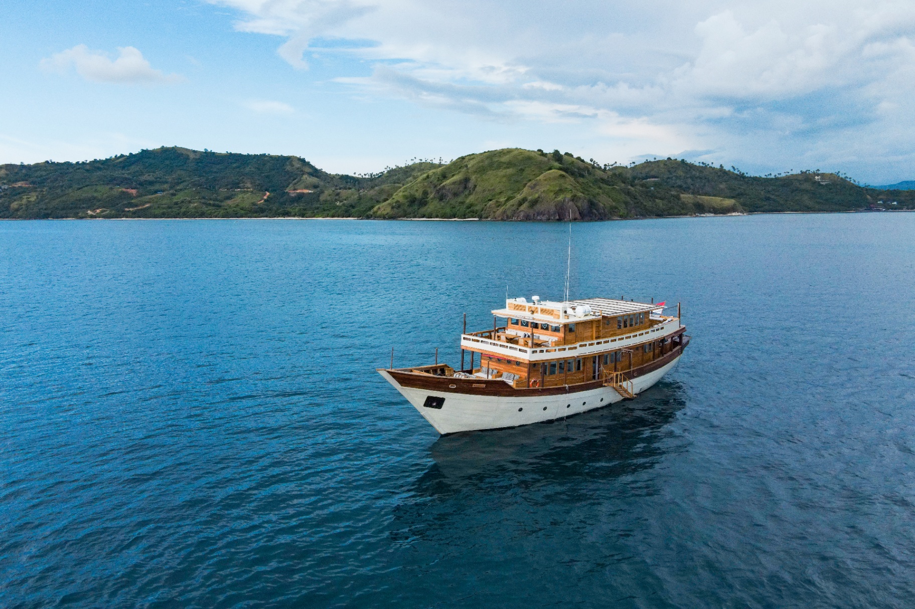 Mischief anchored in calm blue water off the palm-topped hills of Flores