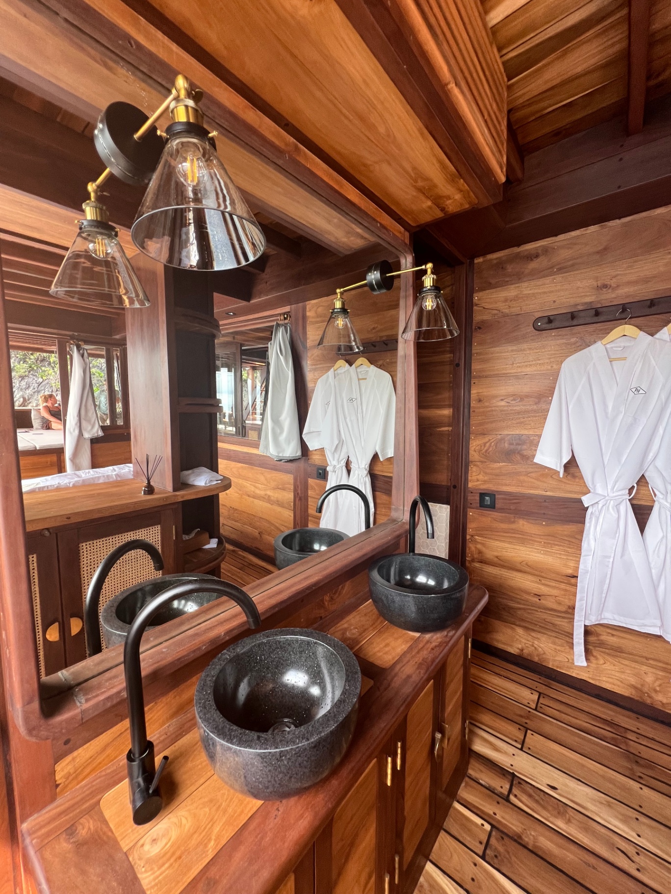 Master bathroom on Dewata with twin stone vessel sinks, brass sconces and robes