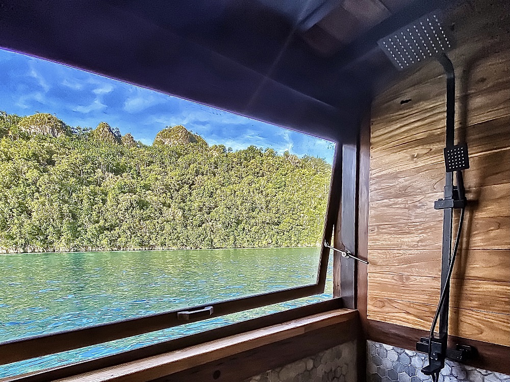 Rain shower on Senja beside a large window over Raja Ampat's jungle and turquoise water