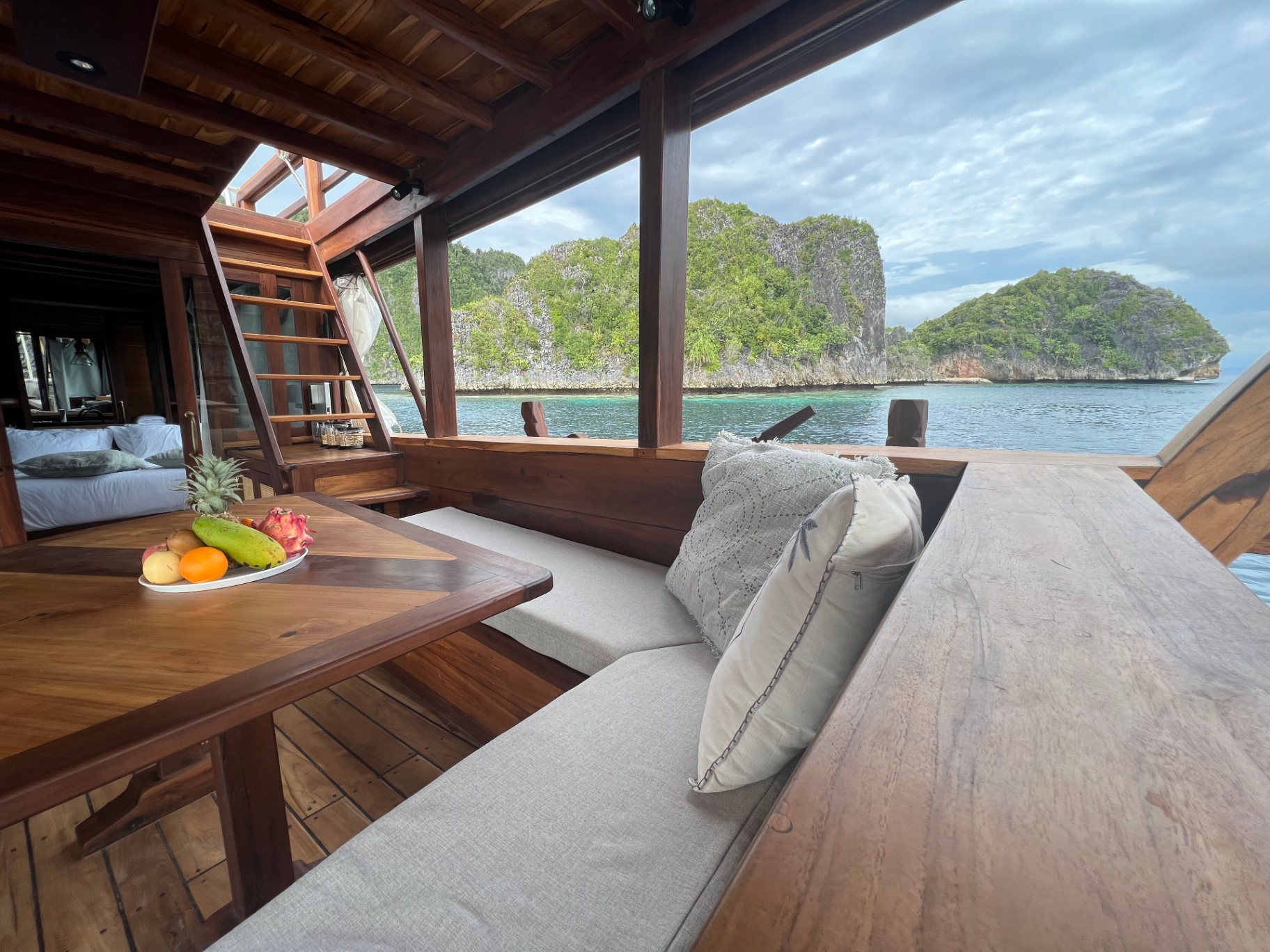 Corner sofa on Dewata's chill deck framing a Raja Ampat karst island view