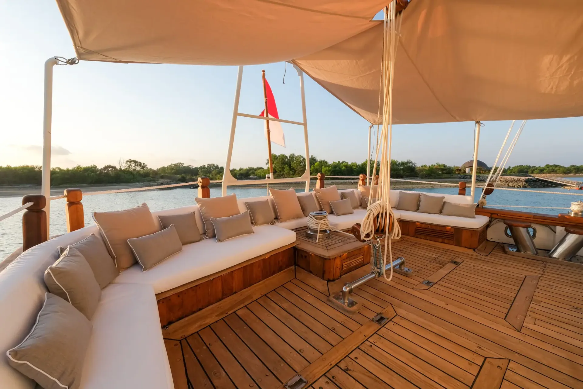 Mutiara Laut shaded bow lounge with curved banquette and Indonesian flag