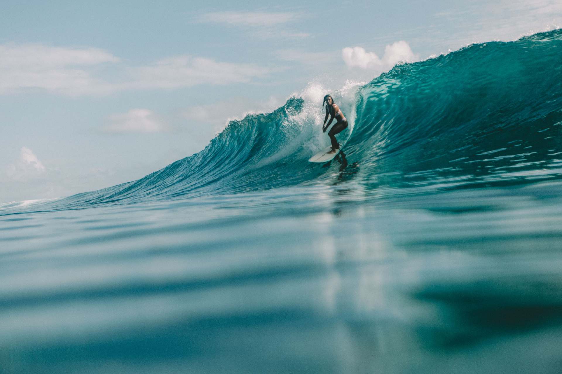 Surfer carving a clean turquoise wave on a Fenides surf charter