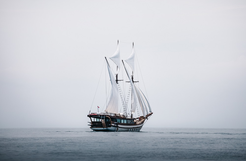 Senja under sail on a moody grey sea seen wide from the side