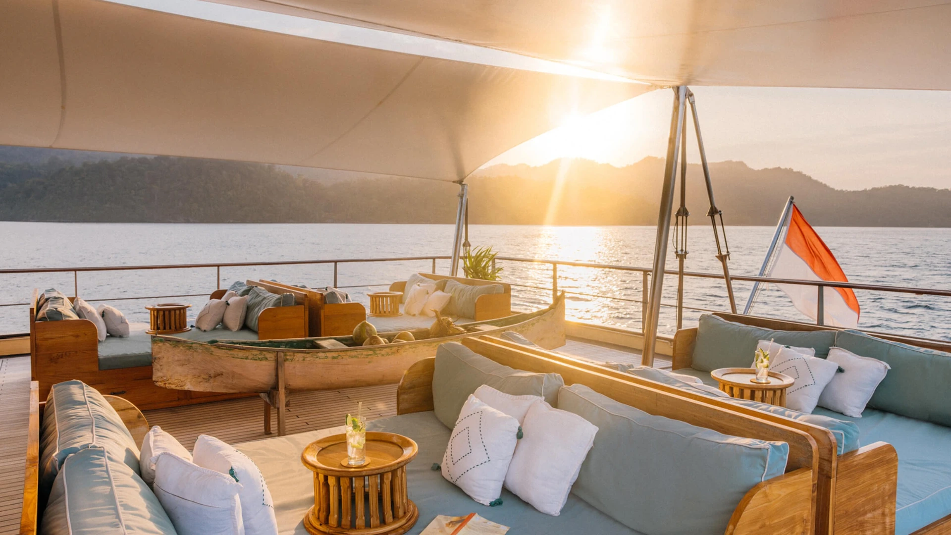 Sunset over the bow lounge on Kudanil Explorer with cushioned banquettes and Indonesian flag