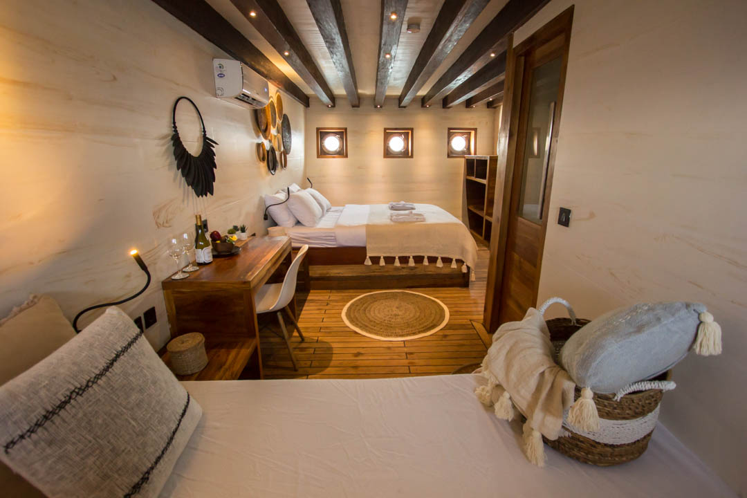Master cabin on Fenides with king bed, writing desk and three portholes