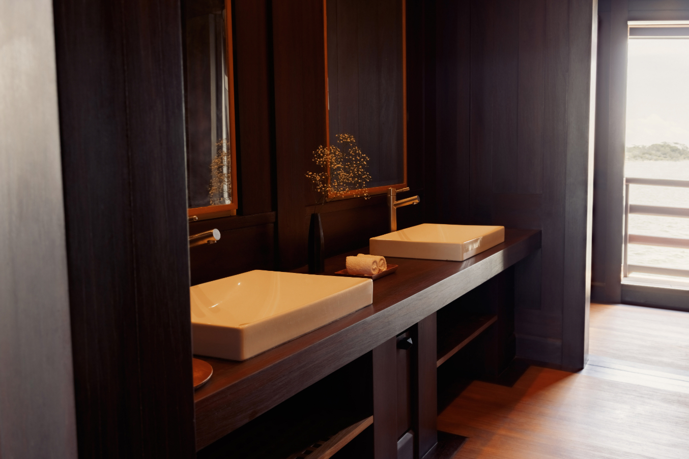 En-suite bathroom with twin vessel sinks on a dark teak vanity and ocean-view window