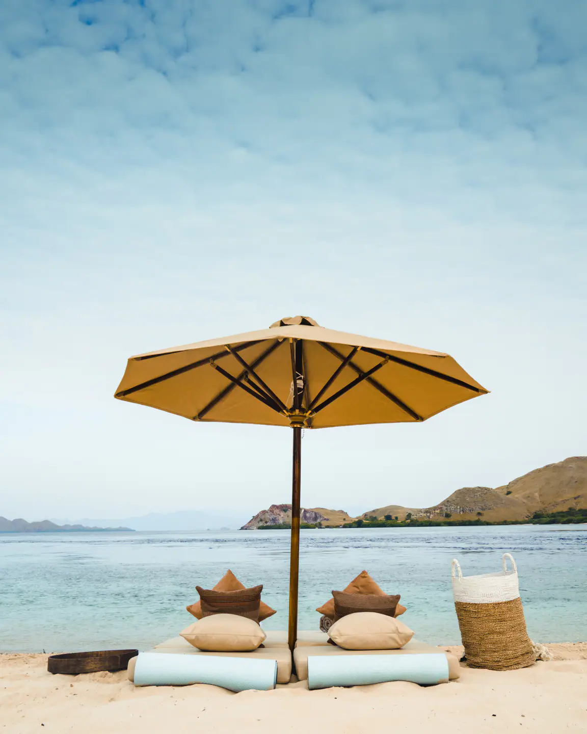 Private beach setup with parasol and daybeds arranged by Celestia crew
