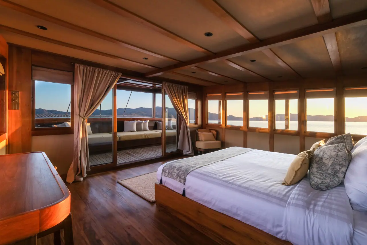 Celestia master stateroom at sunset with private terrace and panoramic windows over Raja Ampat