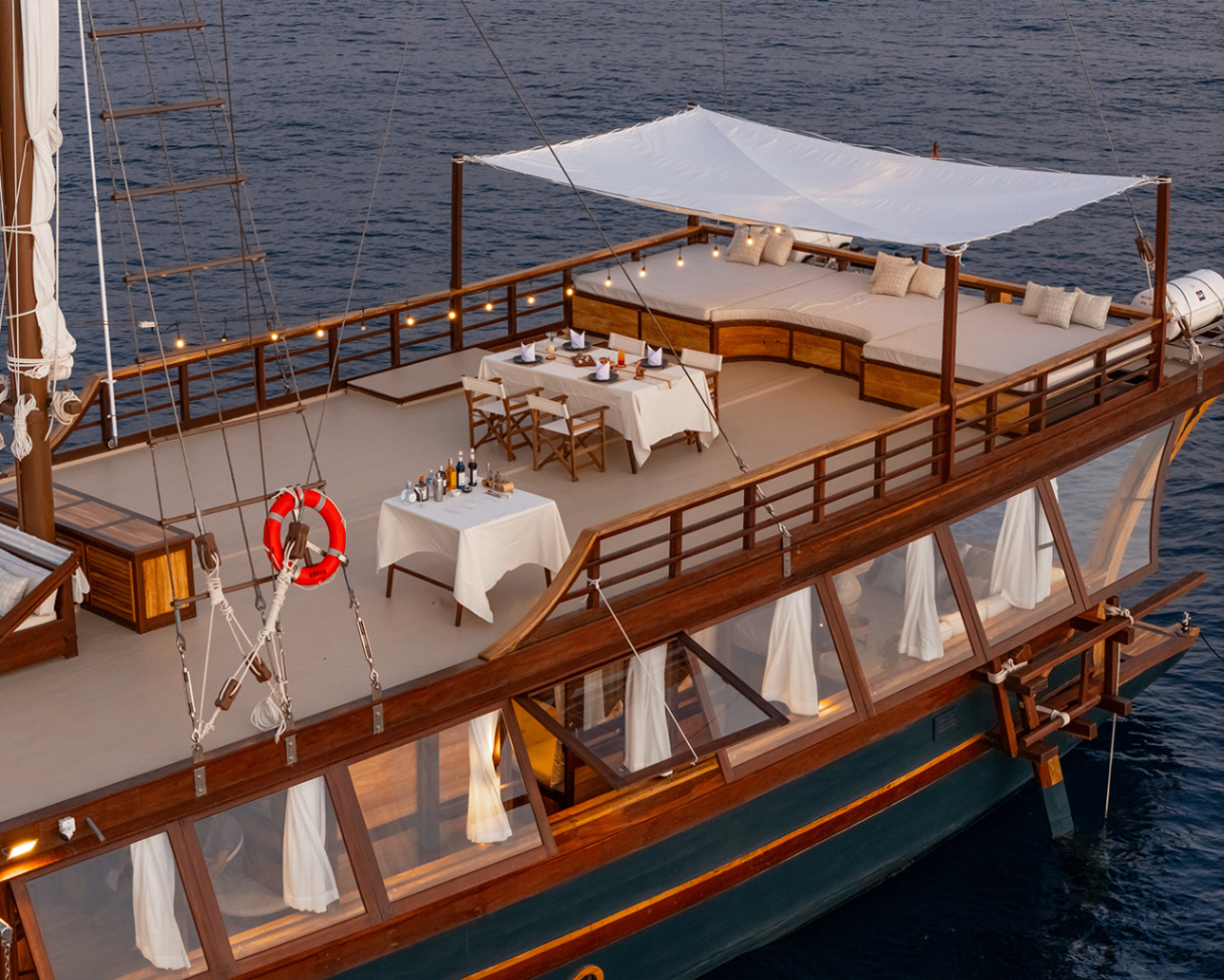 Upper deck of Sanya set for a private dinner beside a large daybed under a white canopy