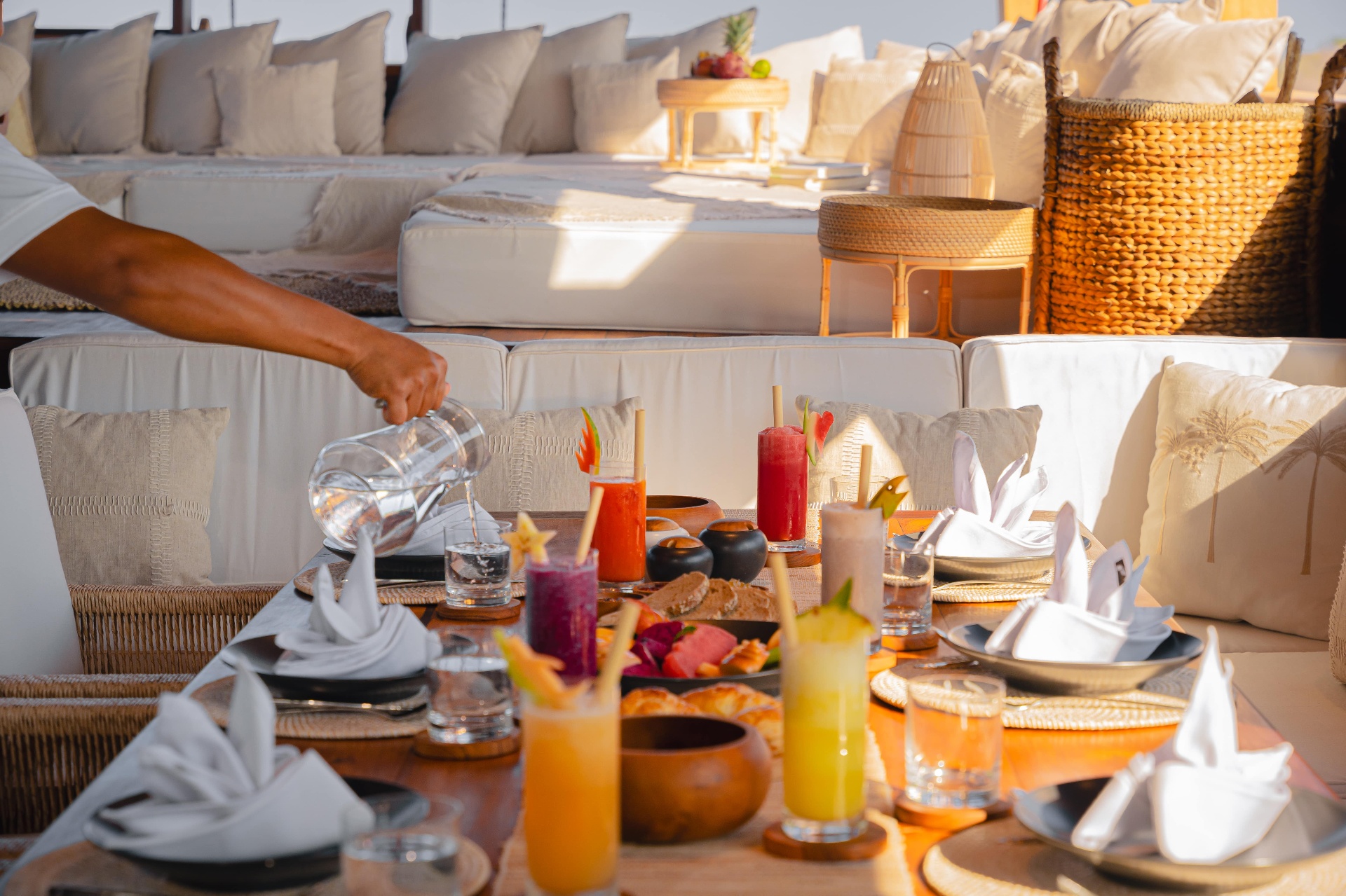 Close-up of fresh juices, cocktails and place settings on Nataraja's main-deck dining table in golden light