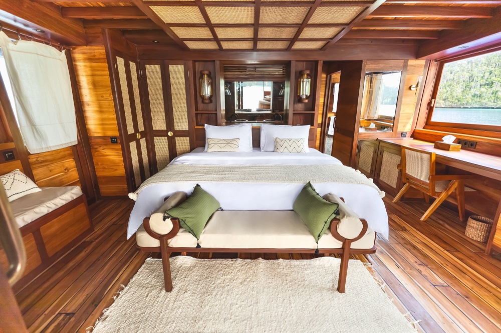 Master cabin on Senja with king bed, writing desk and green cushioned bench at the foot