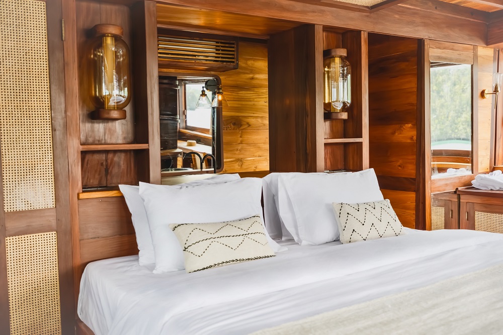 Close-up of Senja's master cabin bed with lantern sconces and cane wardrobe panels