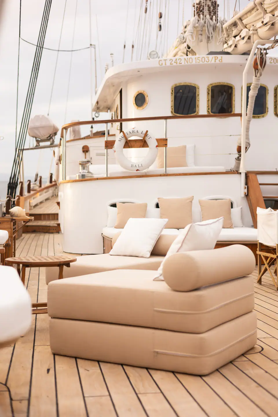 Aft-deck daybed on Mutiara Laut with beige cushions and view of the wheelhouse