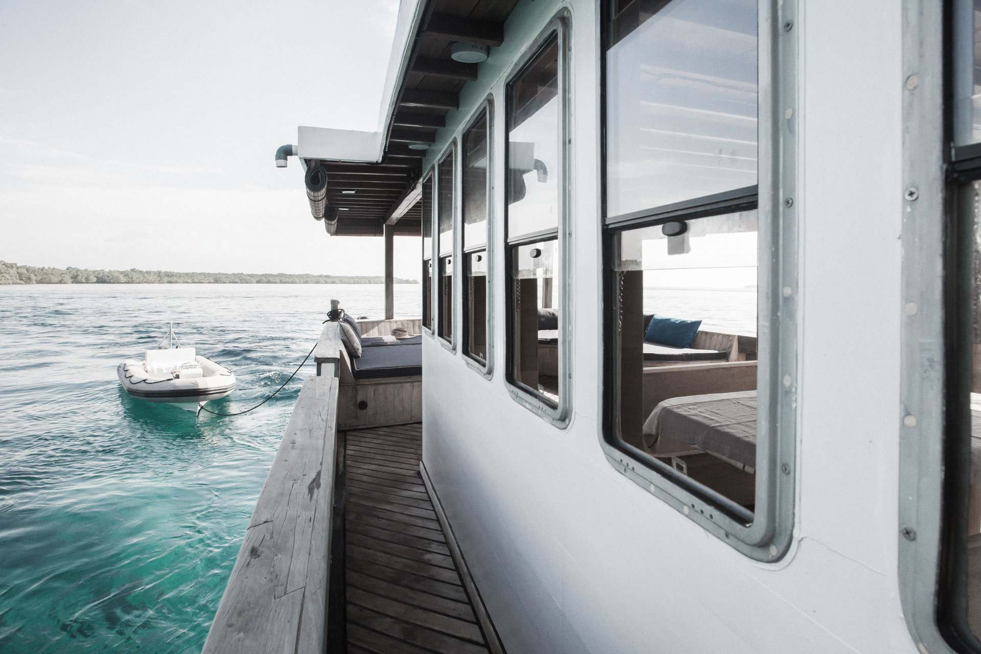 Splendour side deck with day beds and tender tied alongside on clear turquoise water