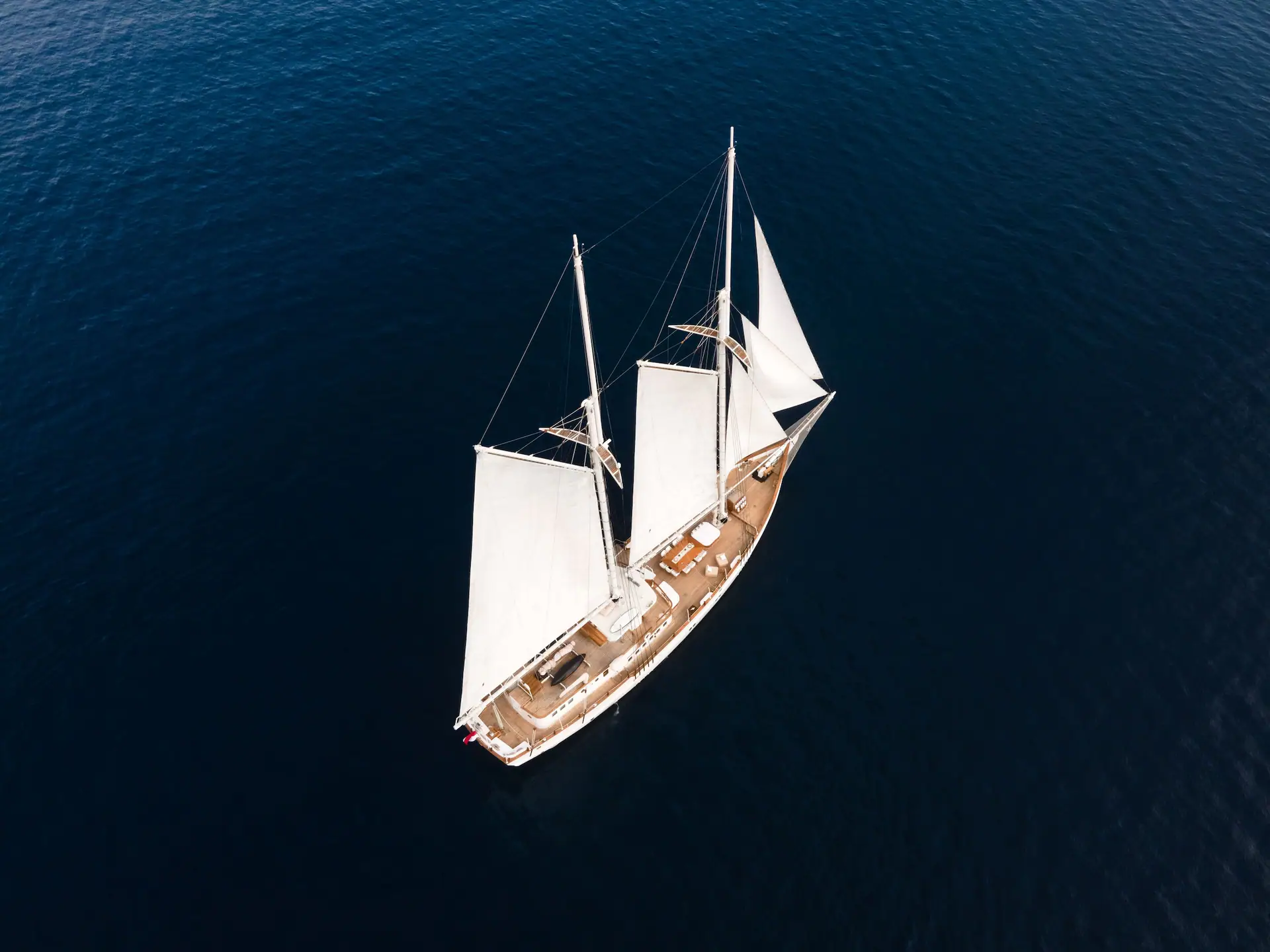 High-angle aerial of Mutiara Laut heeling gently under white sails