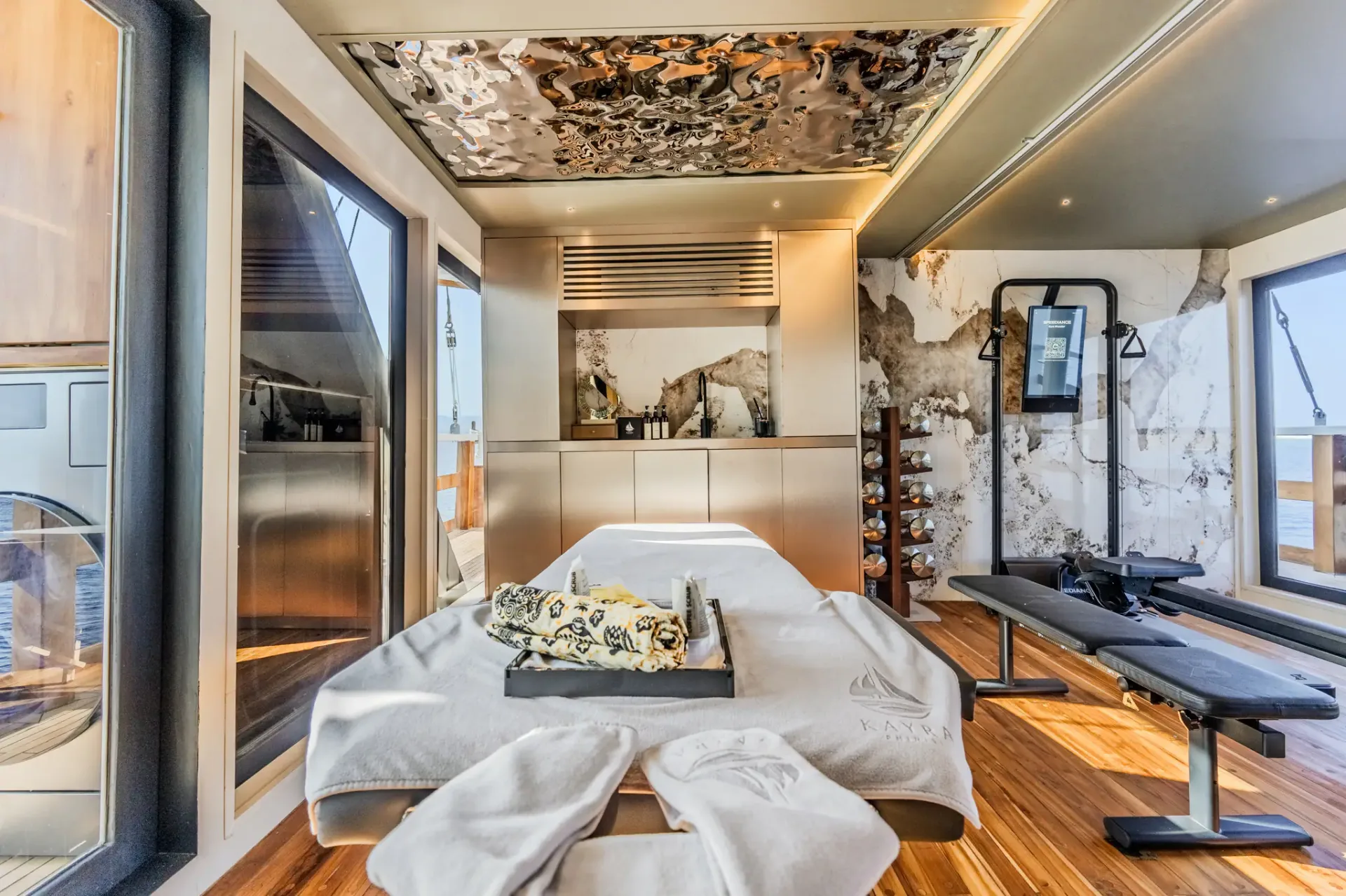 Massage table on Kayra branded with the yacht logo under a mirrored art ceiling