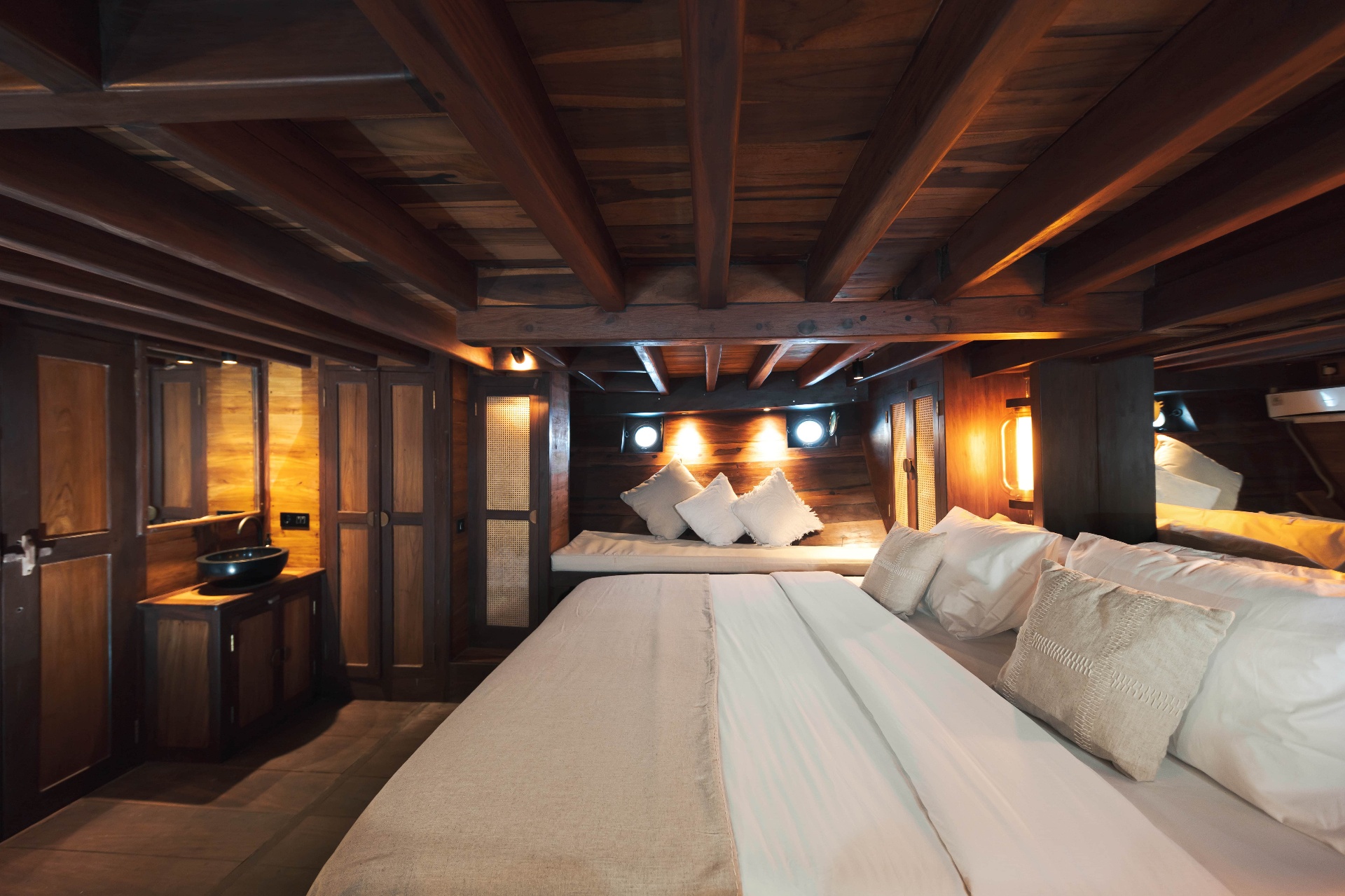 Front cabin on Nataraja seen from the bed with warm lanterns, portholes and a private vanity