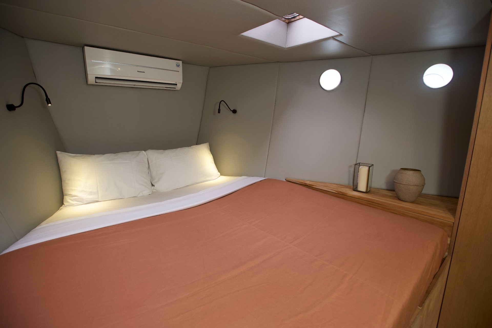 Splendour double cocoon cabin with terracotta bedspread, portholes, skylight and Panasonic air-conditioning