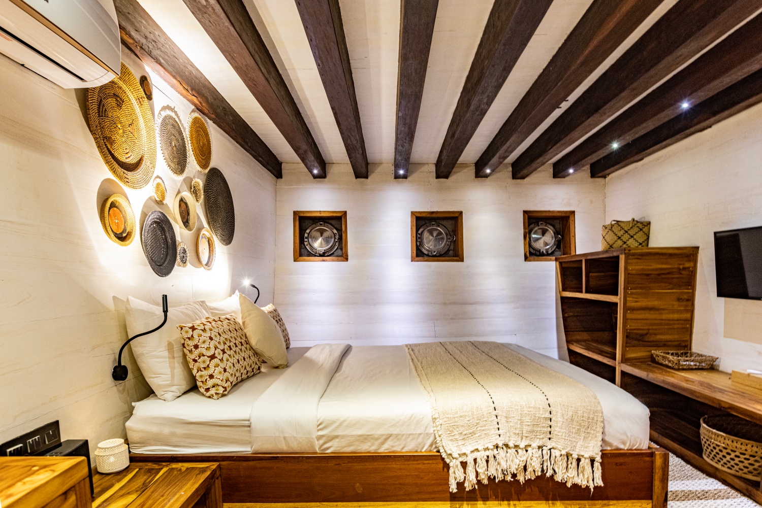 Master cabin on Fenides with king bed, exposed beams and three portholes