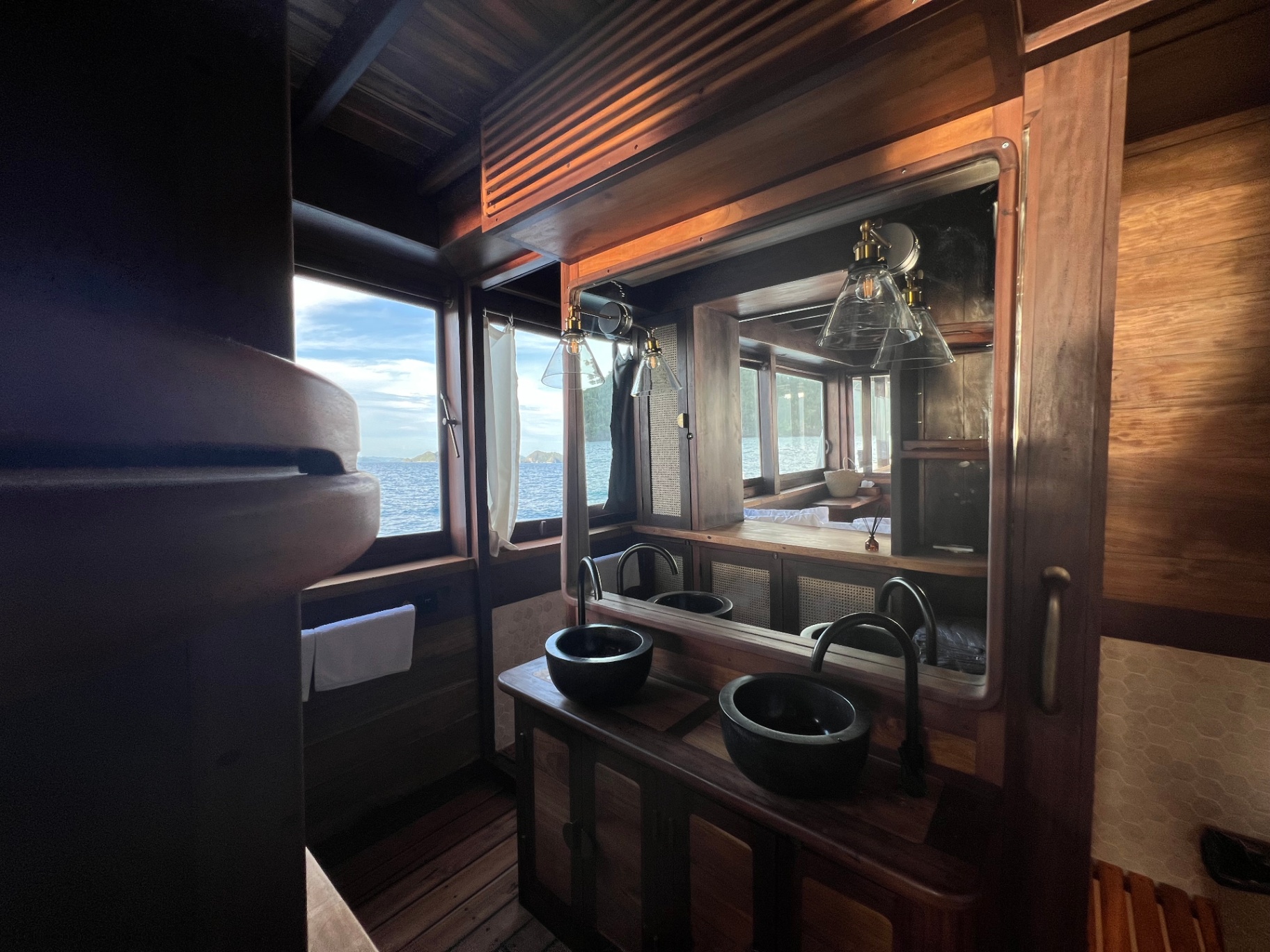 Master bathroom vanity on Dewata with black stone sinks and a window over the sea