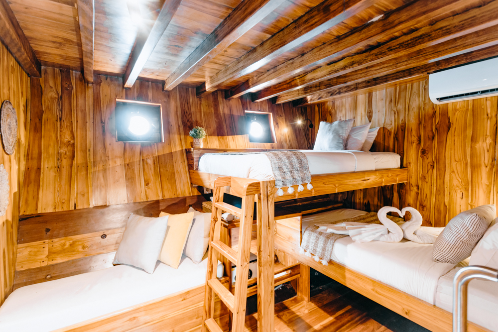 Andamari bunk cabin with wooden bunk beds, ladder, teak walls and porthole windows