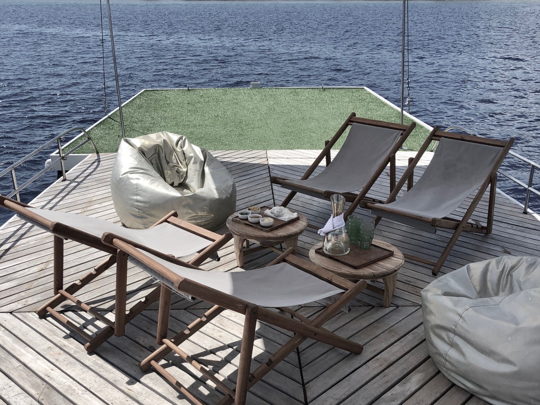Splendour sun deck set with loungers, bean bags and drinks overlooking open water