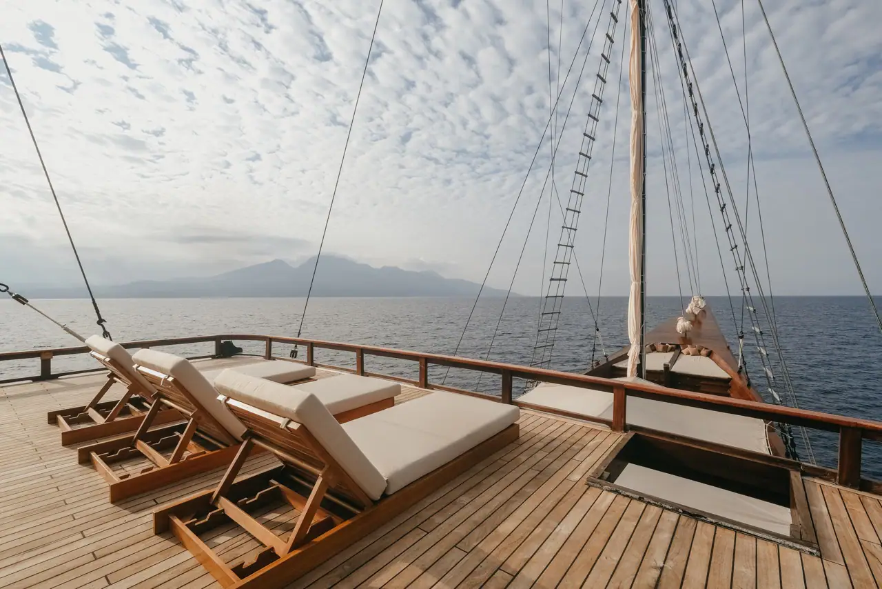 Celestia upper sundeck with teak sun loungers and volcano view
