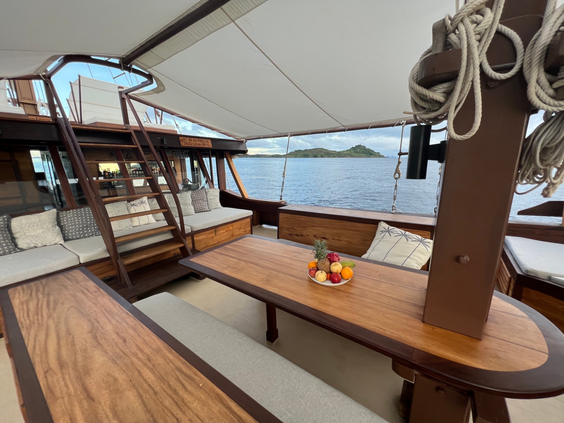 Shaded foredeck dining table on Dewata at first light with fruit platter