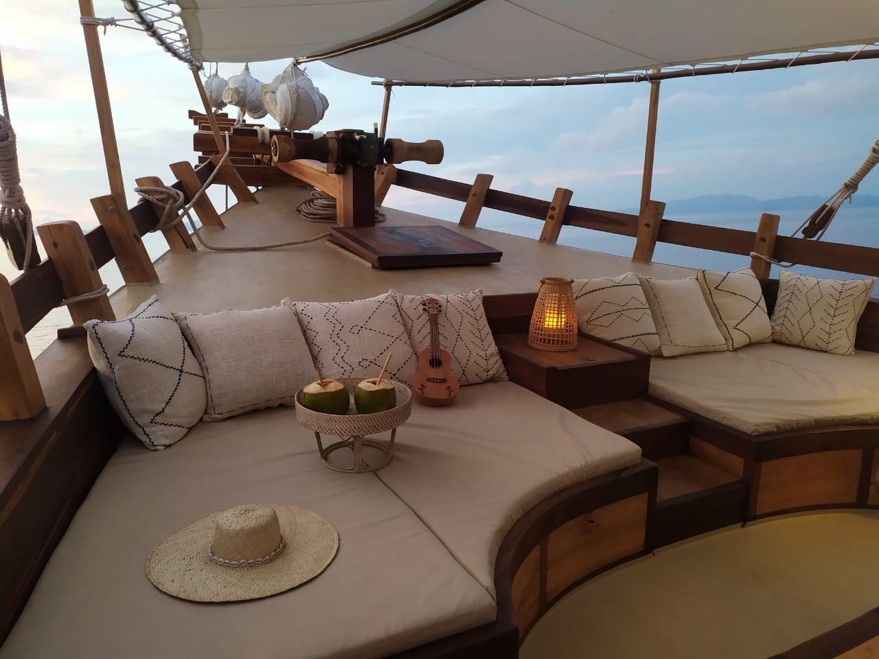 Bow lounge on Senja at sunset with cushions, ukulele and coconuts, distant island on the horizon