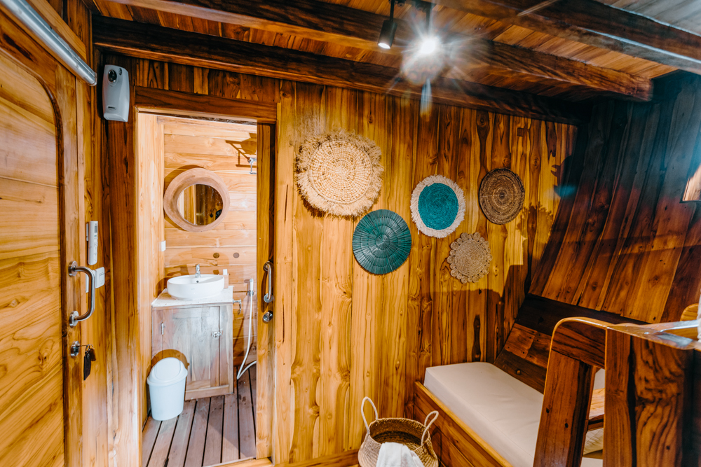 Andamari cabin ensuite entry with woven wall art and teak paneling