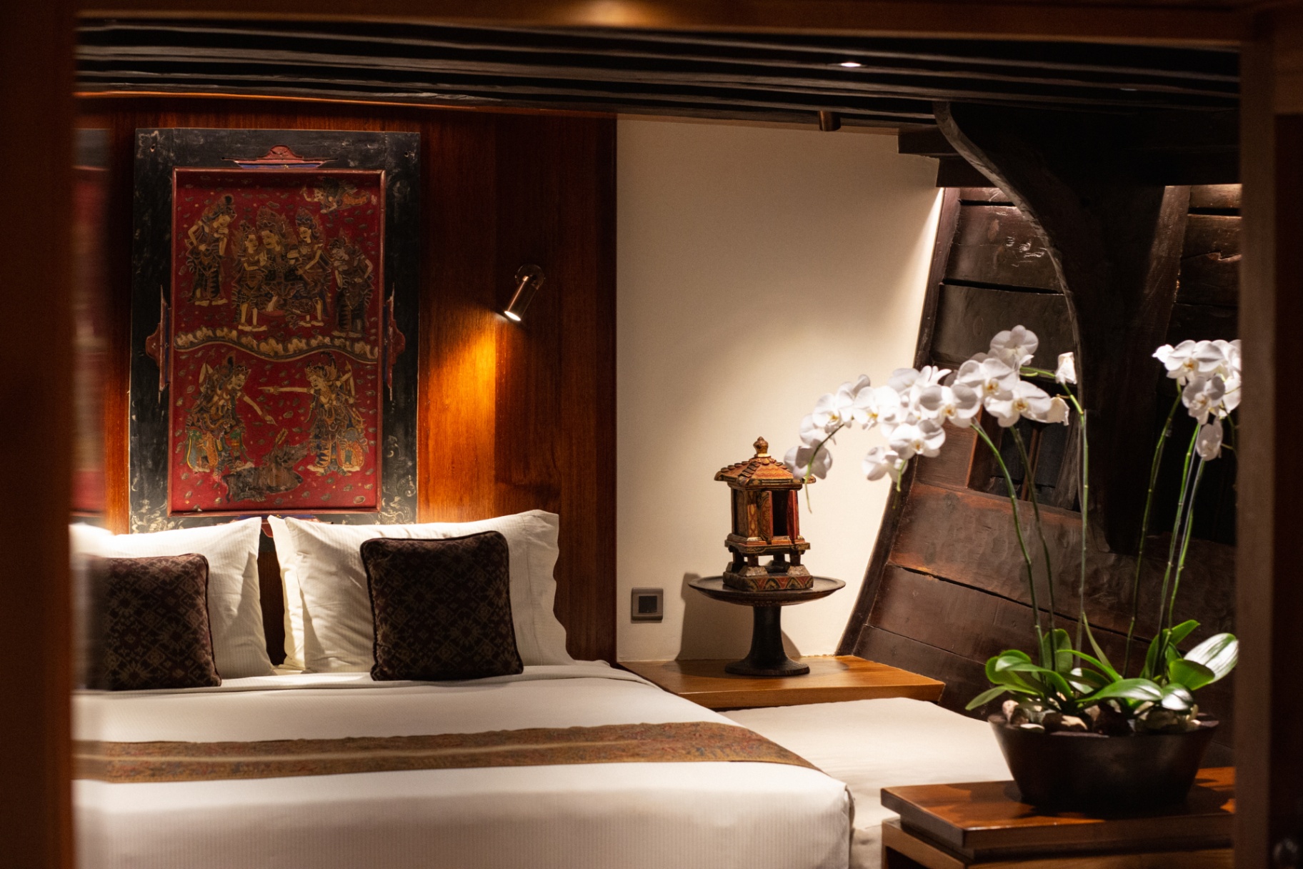 Suite on Silolona with antique red Balinese painted panel above the bed and orchids