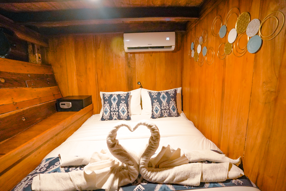 Double cabin on Adishree with metal disc wall art, in-cabin safe and turndown towel swans on the bed