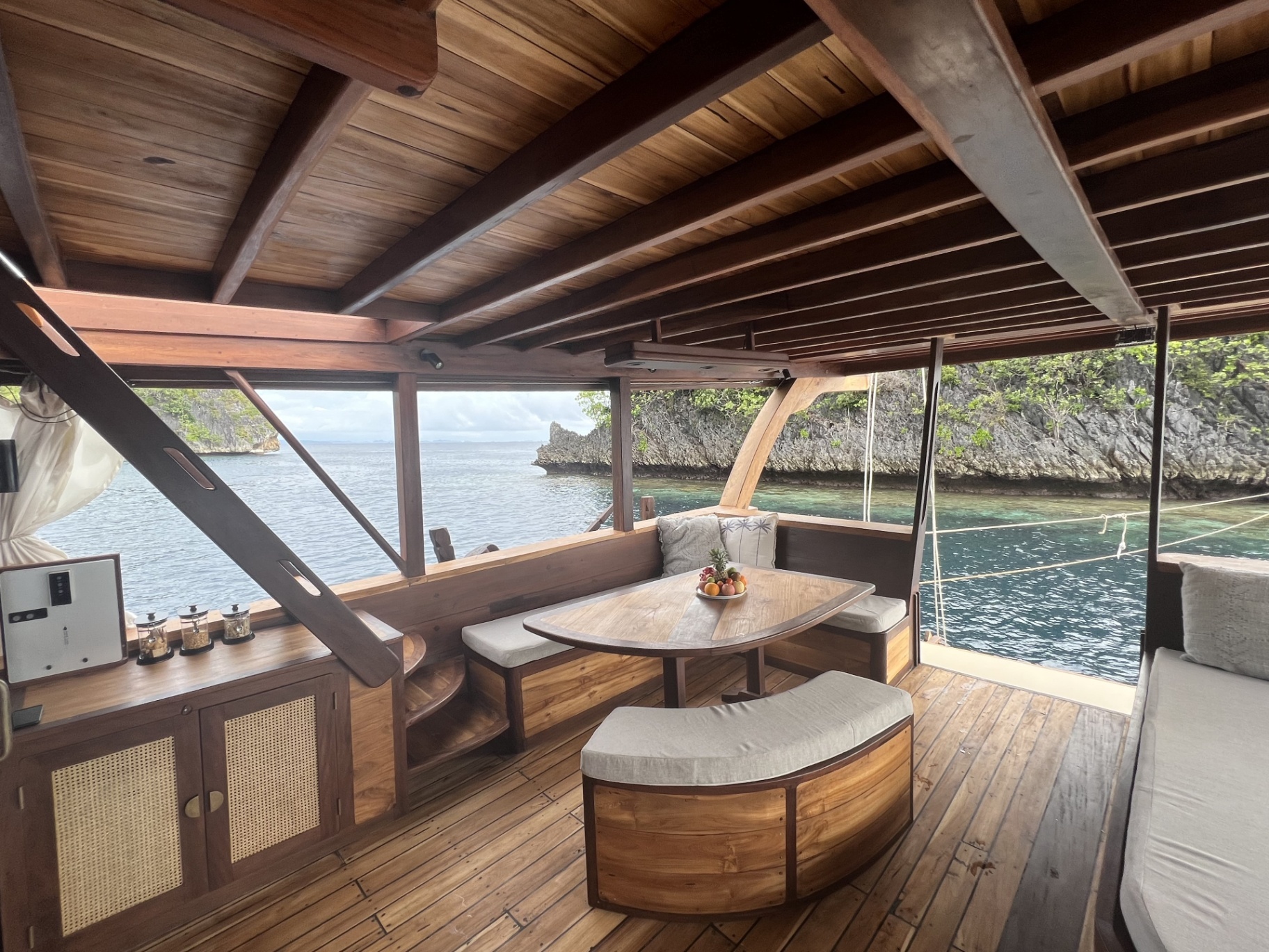 Dining nook on Dewata's chill deck with fruit platter and open sea view