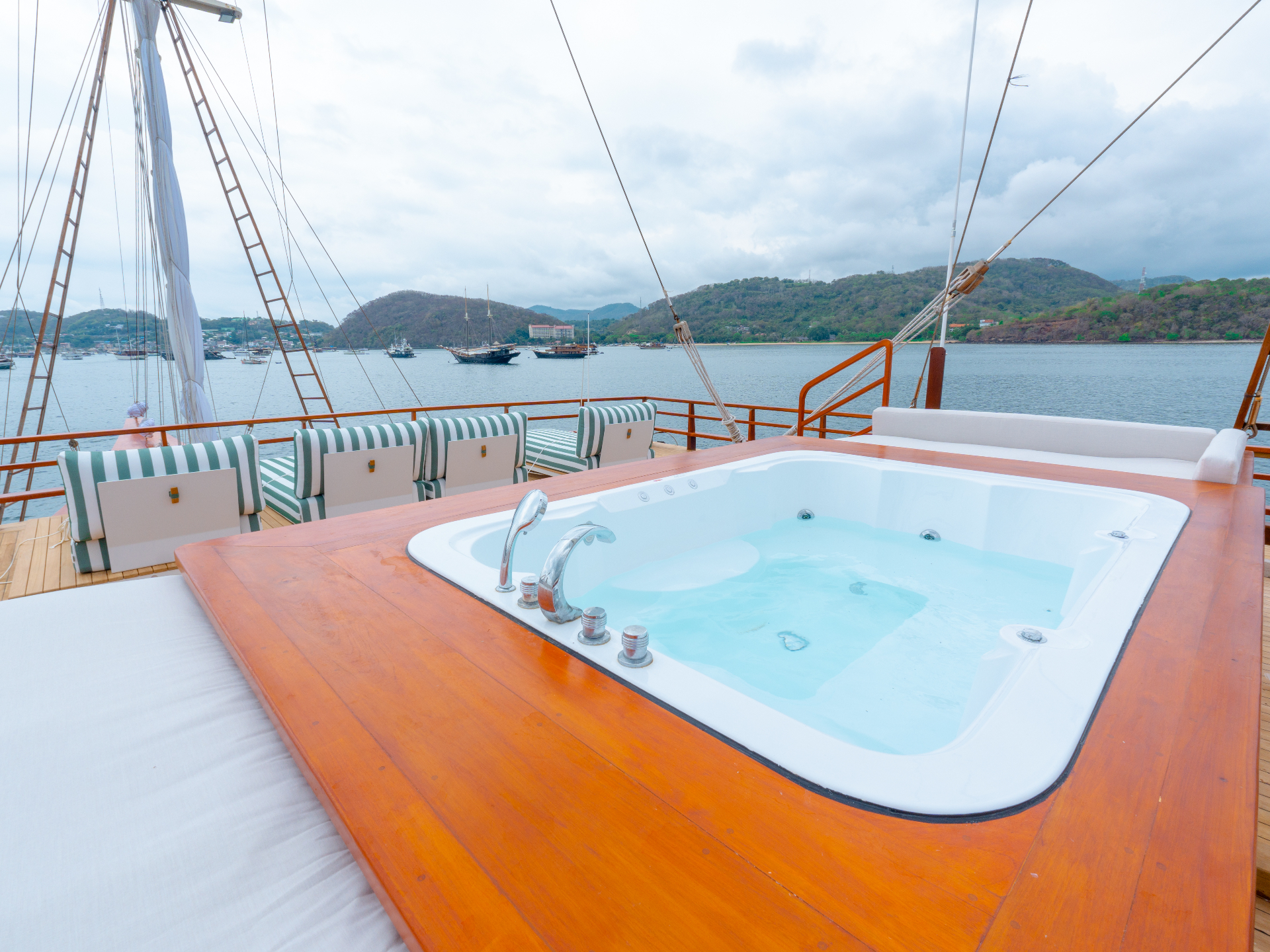 Top-deck jacuzzi on Sanctuary with striped sun loungers and views over Komodo bay
