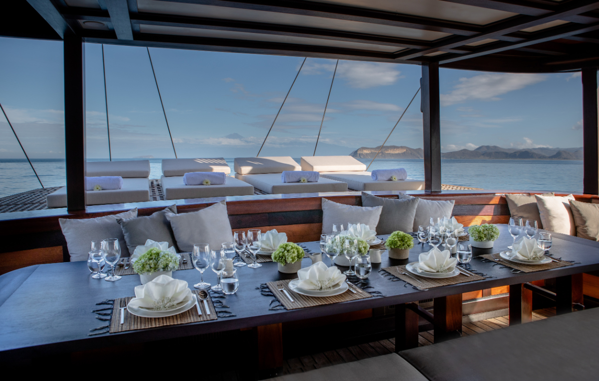 Al fresco deck dining table with hydrangeas and ocean-view daybeds beyond
