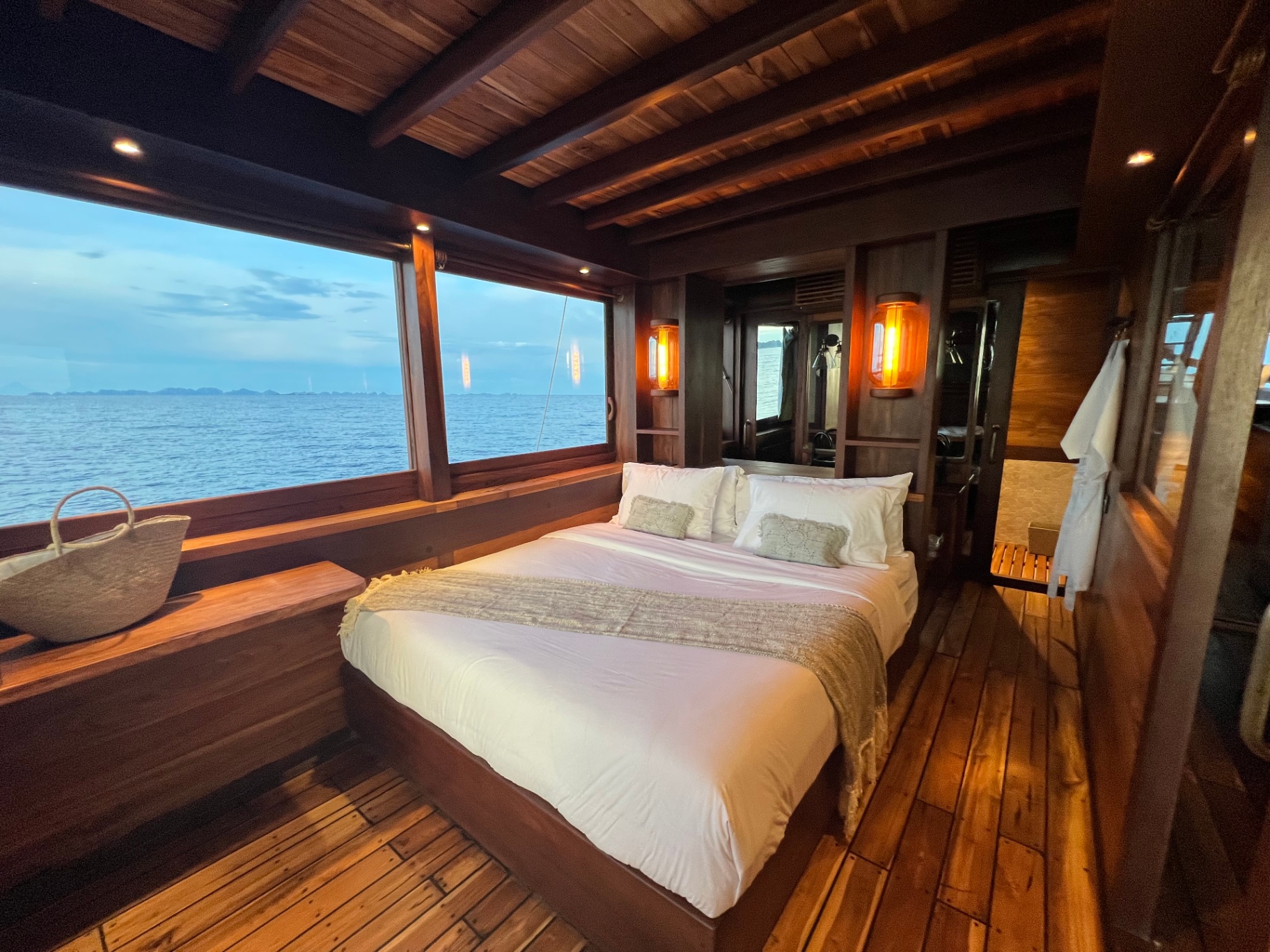 Dewata master cabin at blue hour with warm lantern glow and ocean view